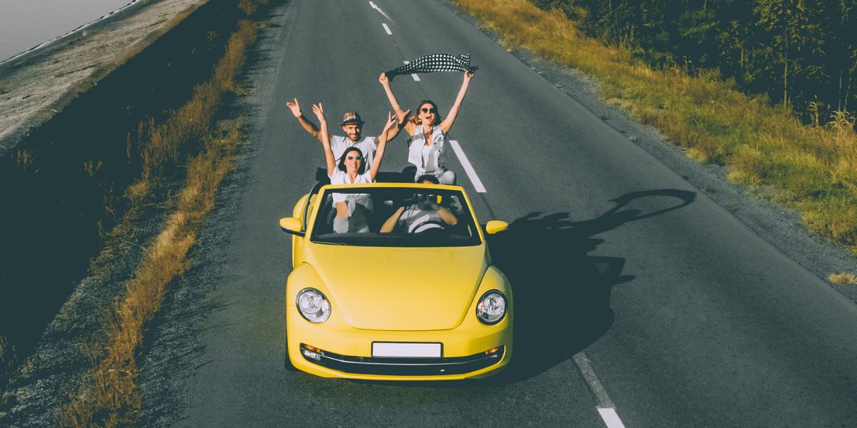 Four friends traveling on road in yellow car