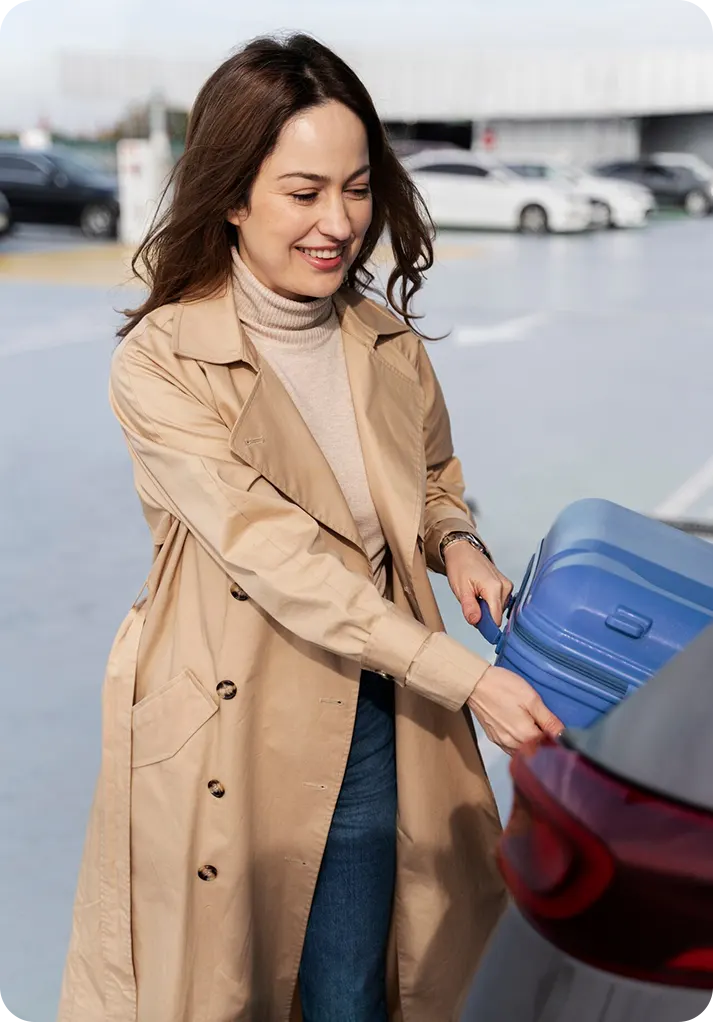 A woman in a navy hijab sits in a car, holding a phone to her ear. She looks thoughtful, gazing outside. The interior is neutral-toned, creating a calm mood.